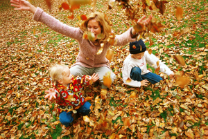 Mother and kids in meadow with fall leaves